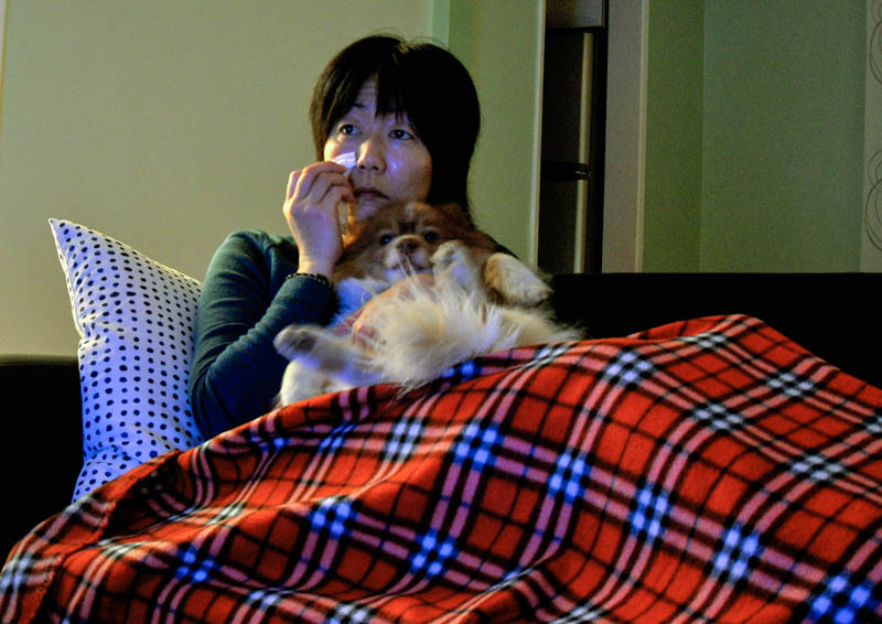 photo of Jennifer Moon sitting on the couch holding Mr. Snuggles and crying in the light of a TV